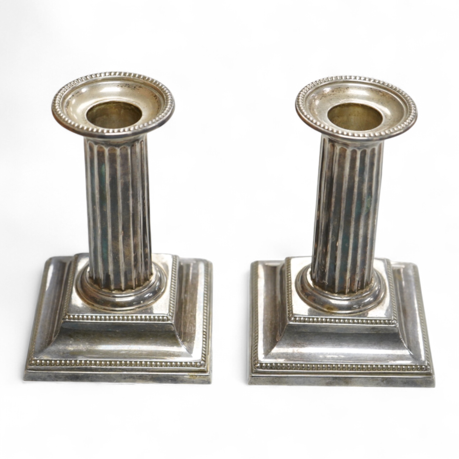 A pair of Edwardian silver mounted fluted column candlesticks, by Hawksworth, Eyre & Co, Sheffield, 1905/6, height 12cm, weighted.
